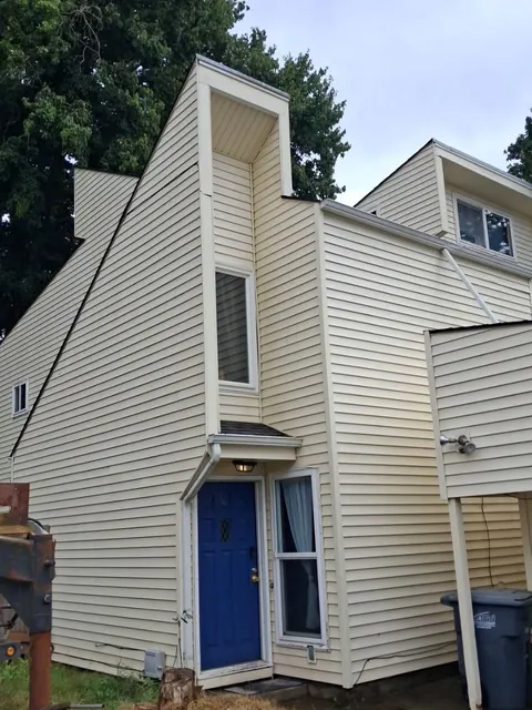Light-colored siding and trim frame a vivid blue front door beneath the tall roofline.
